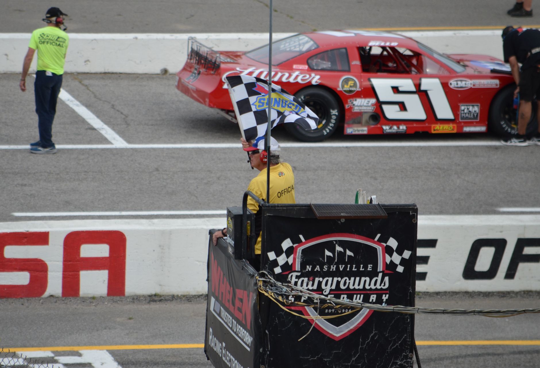 A checkered flag waving at the finish of a short track race