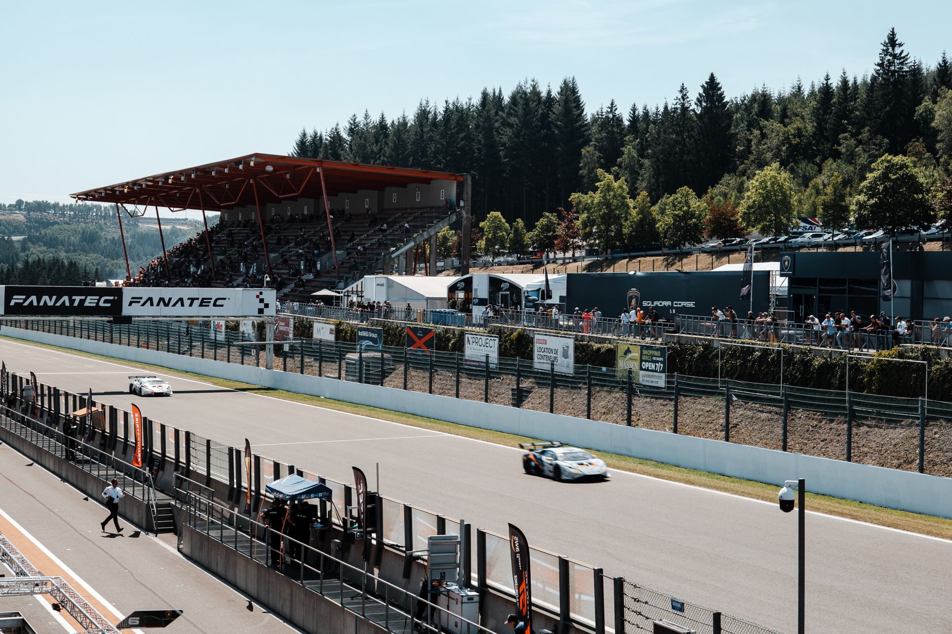 Race cars on track in front of a grandstand of spectators